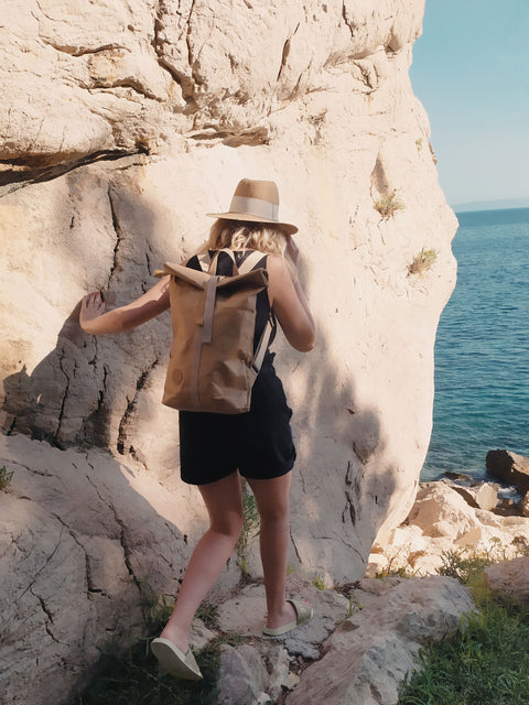 nő hátizsákkal egy szikla mellett